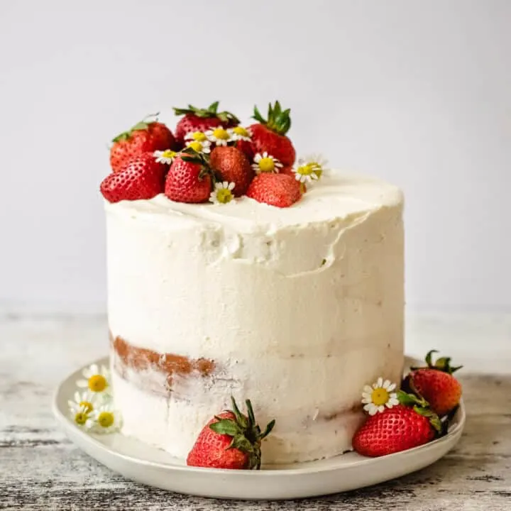 Cake with white frosting and fresh strawberries on top.