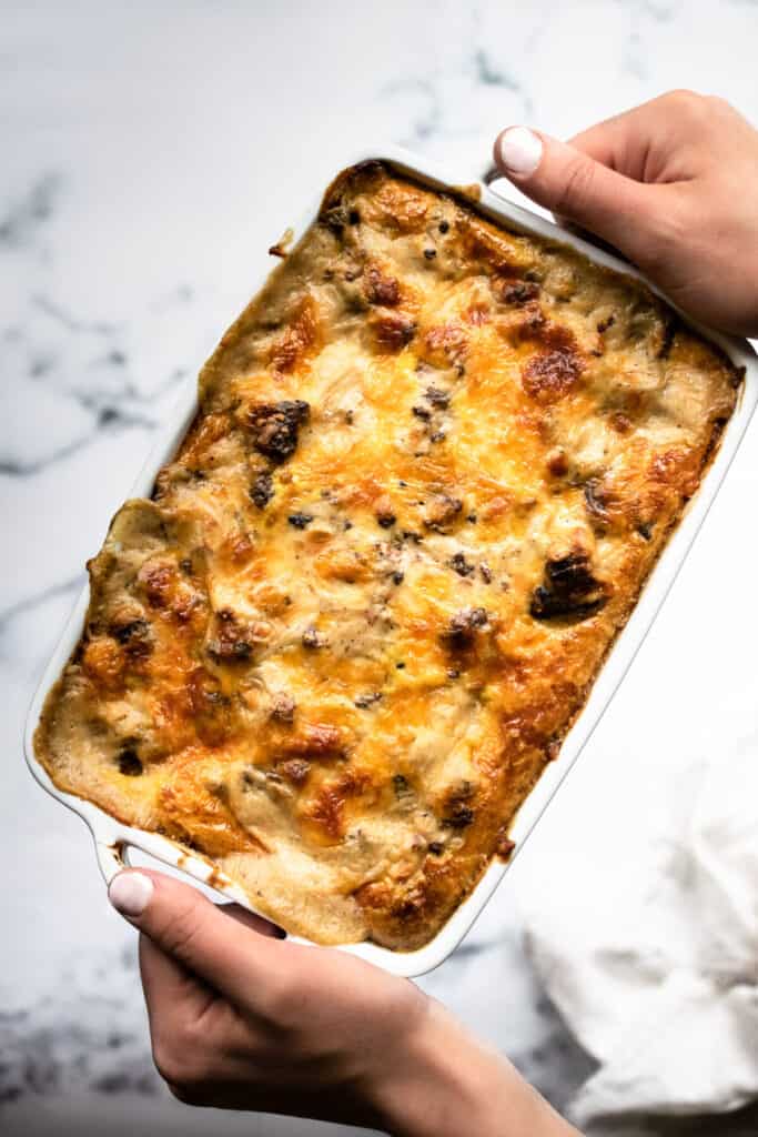 Rectangular casserole dish with potatoes, sausage gravy, eggs and cheese.