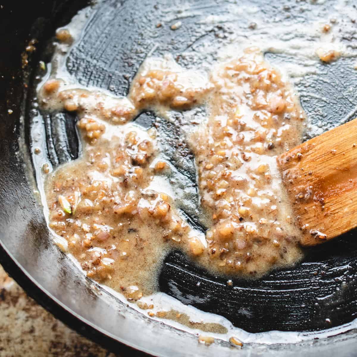 A roux made from flour, butter, garlic and shallot in a skillet. 