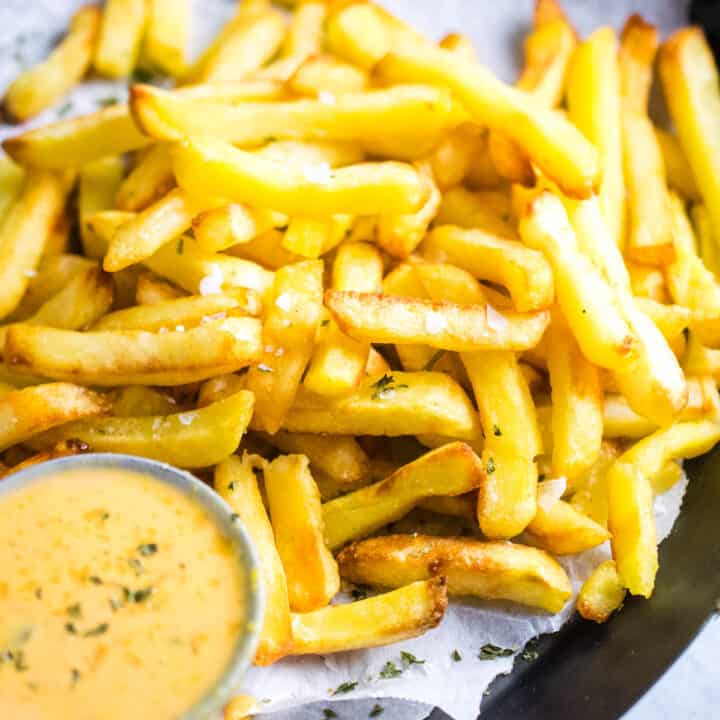 Air fried French fries on a platter with dipping sauce.