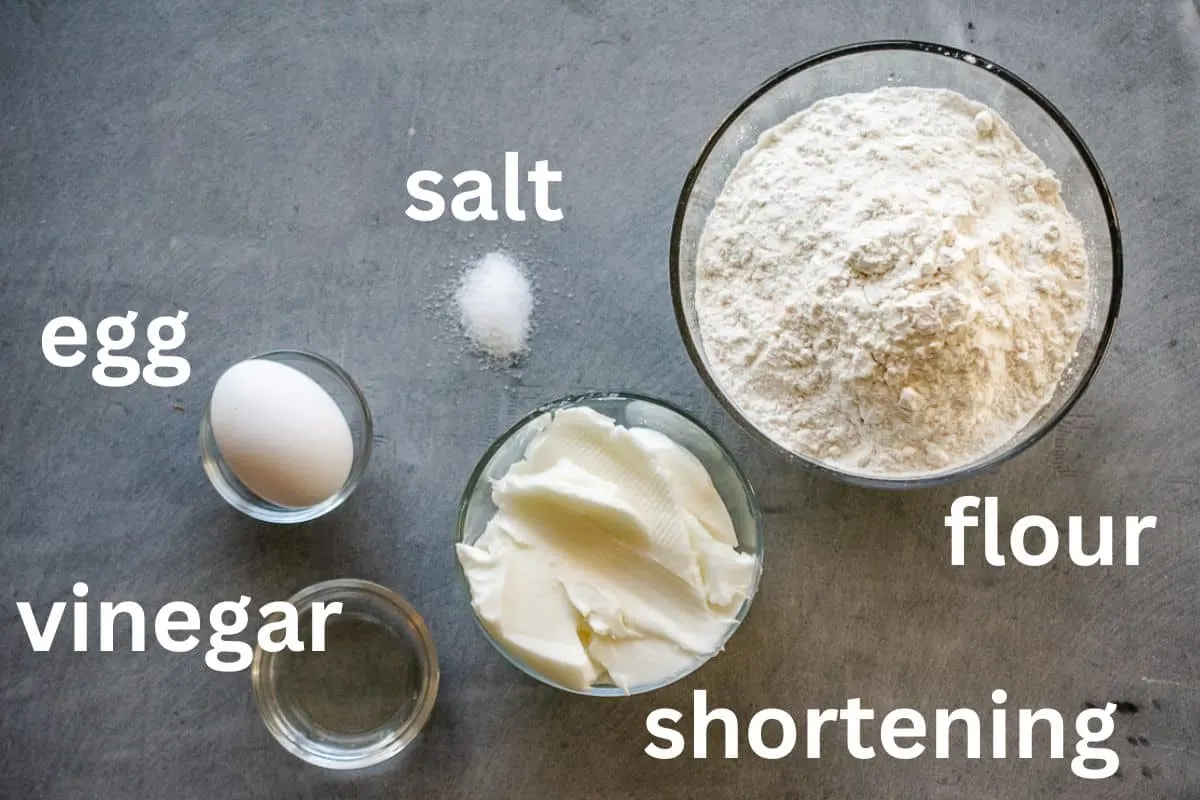 Flour, shortening, egg, salt, and vinegar in bowls for making Crisco pie crust. 