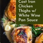 Chicken thighs in a cast iron skillet in a white wine pan sauce with rosemary and garlic.