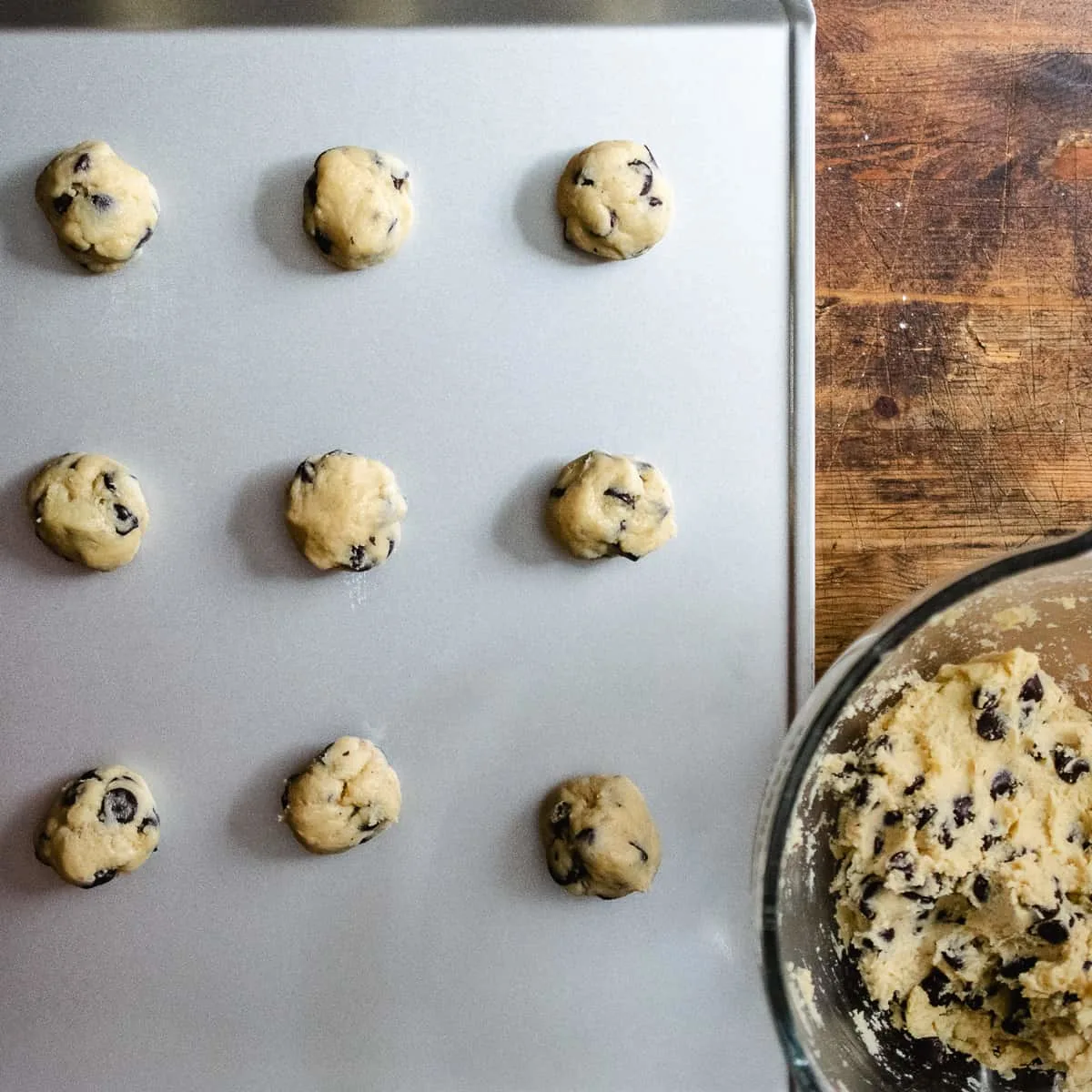 Chocolate chip cookie dough rolled into balls on a cookie sheet.
