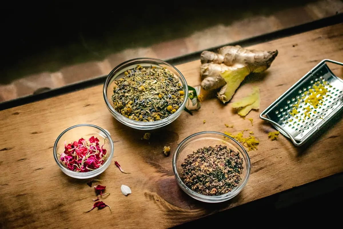 Chamomile, ginger root, rose petals, hibiscus tea, lemon zest and mixed tea on a window sill in the moonlight.