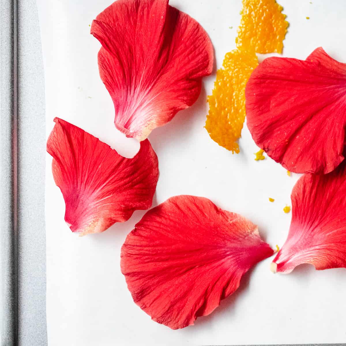Hibiscus petals and orange peel on a baking sheet.