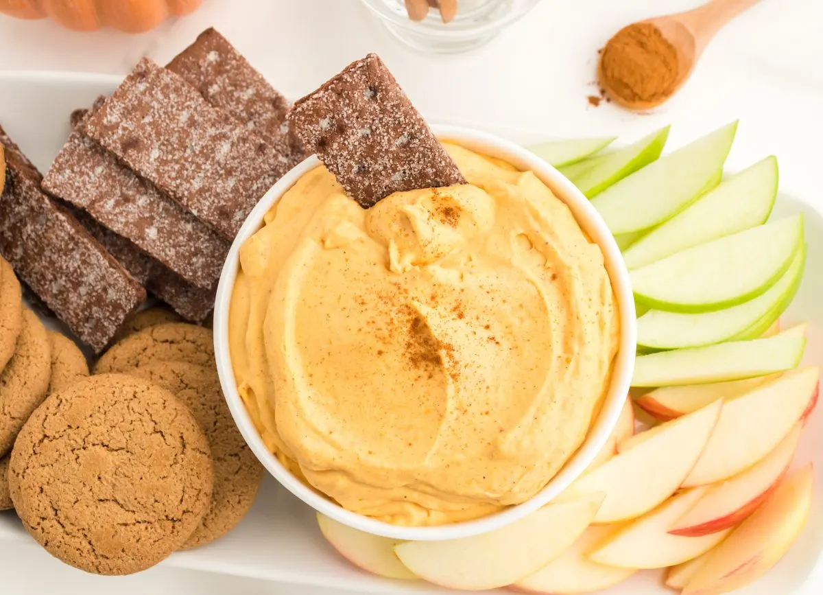 Looking down on a spread of graham crackers, ginger snaps, and apple slices with a bowl of Pumpkin Dip.