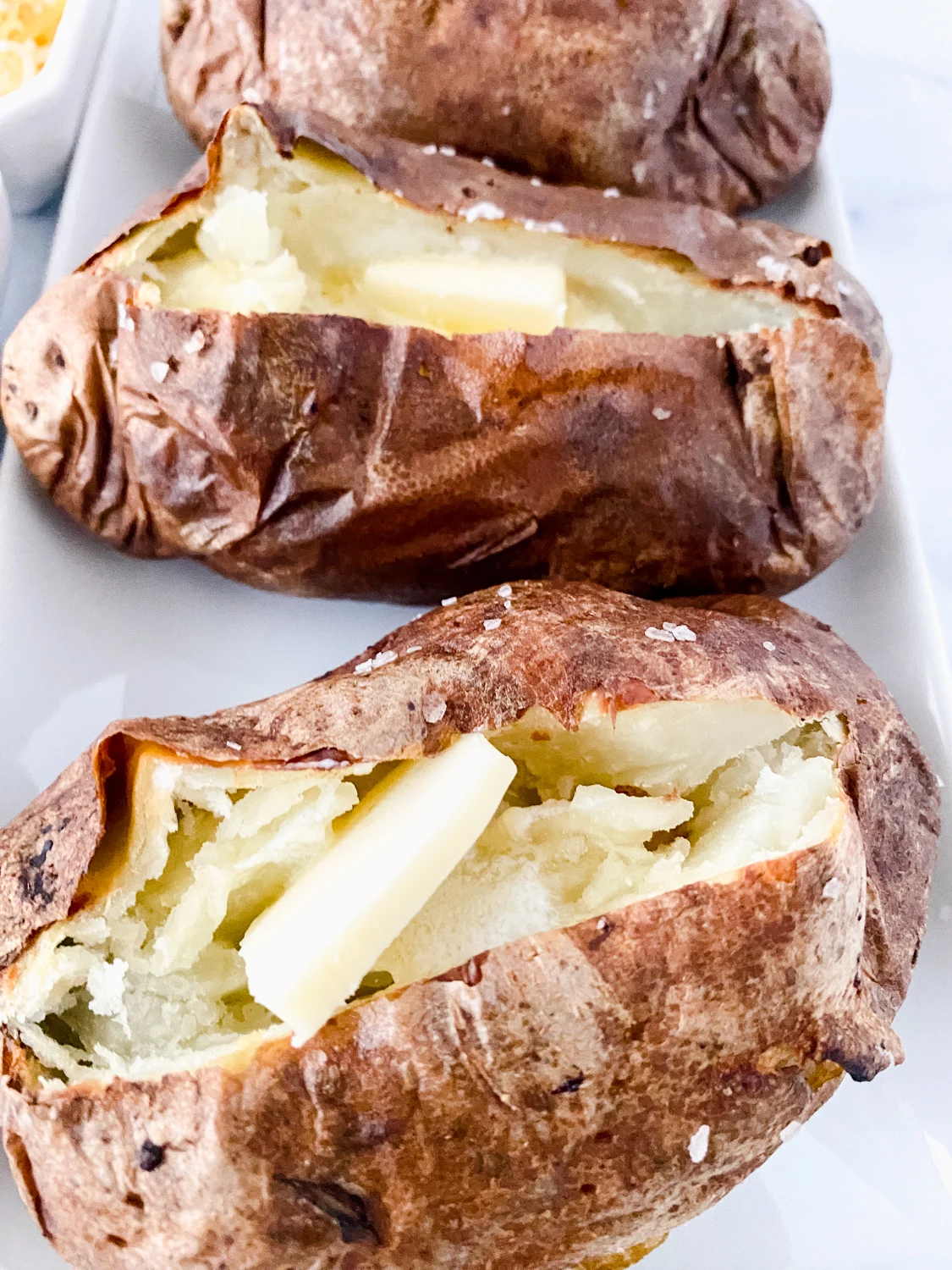 baked potatoes made in the air fryer served with salt, butter, cheese, and bacon