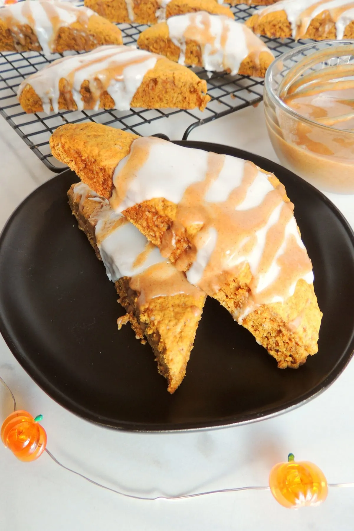 A black plate with a few homemade Pumpkin Scones with a glaze.