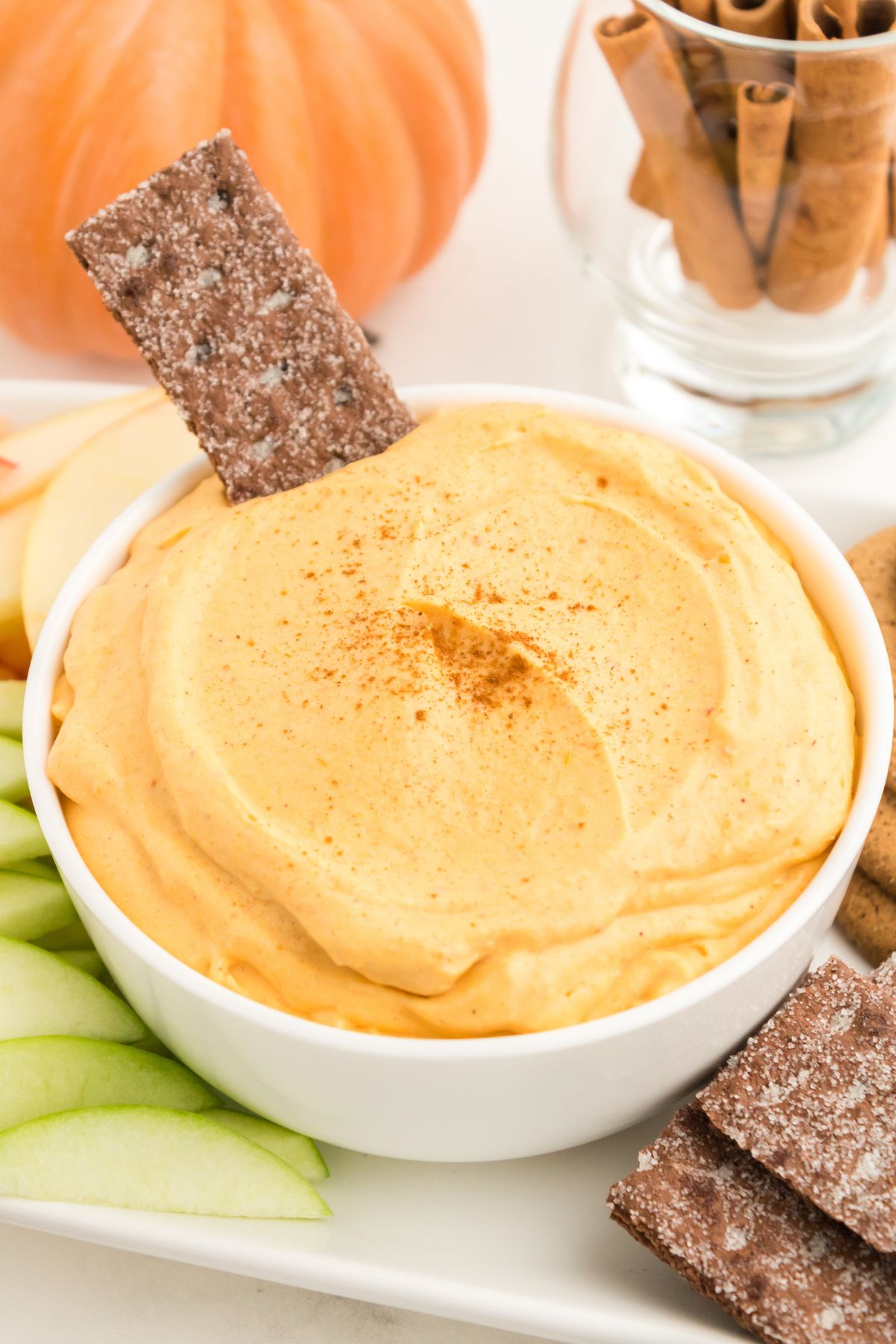A single chocolate graham cracker in a bowl of creamy pumpkin dip.