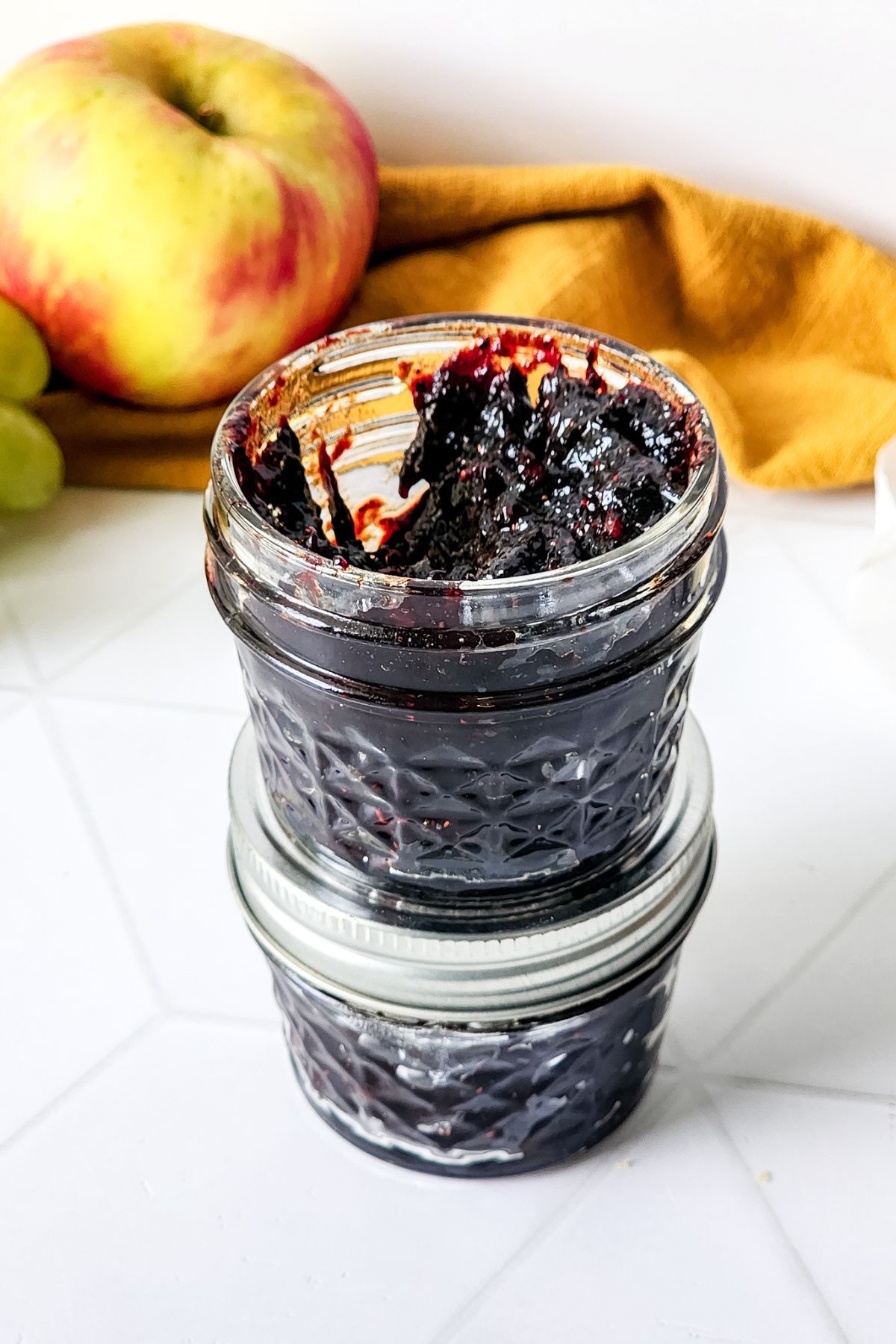 An open jar of Mixed Berry jam sitting on a closed one.
