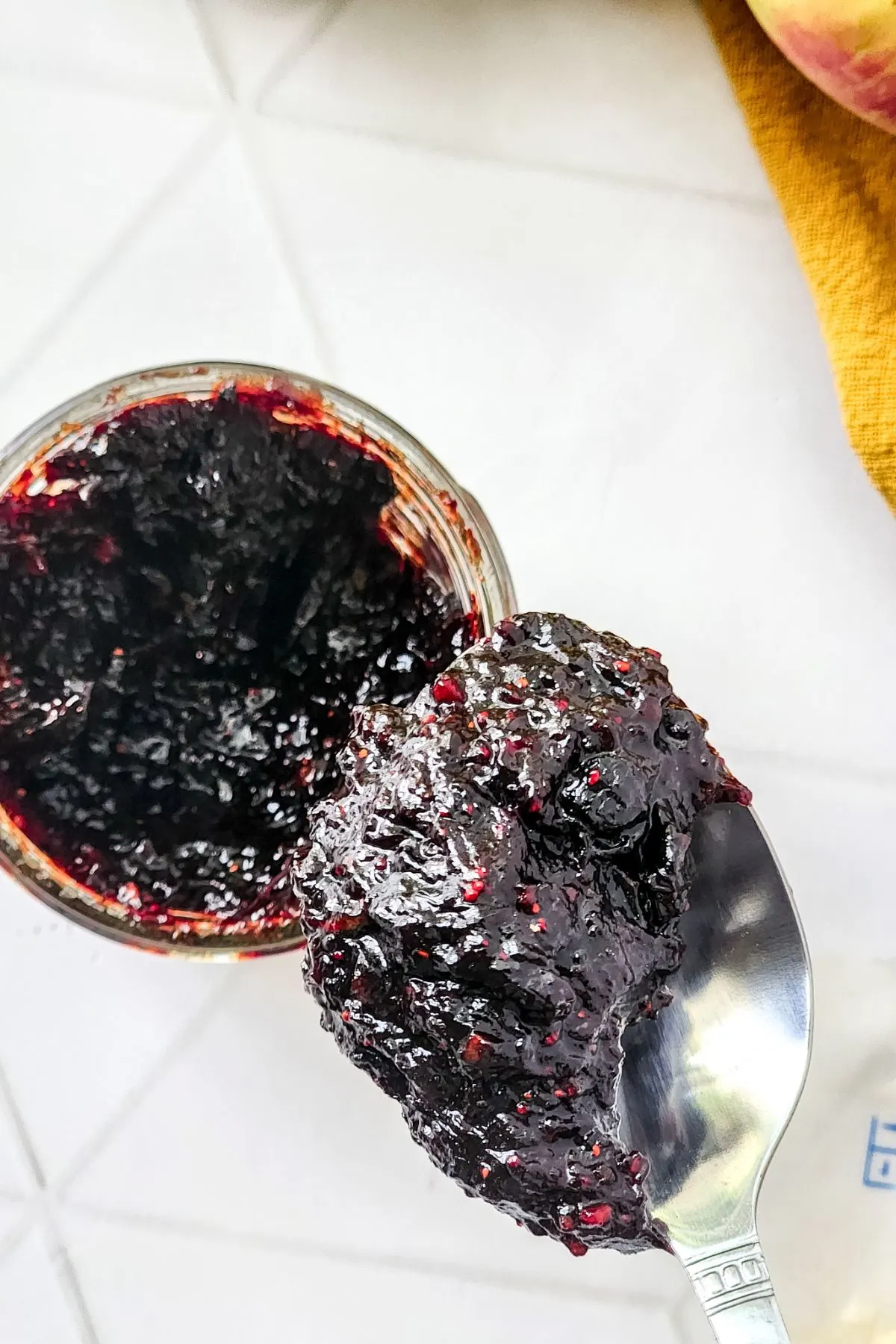 A spoon of Mixed Berry Jam with the jar.