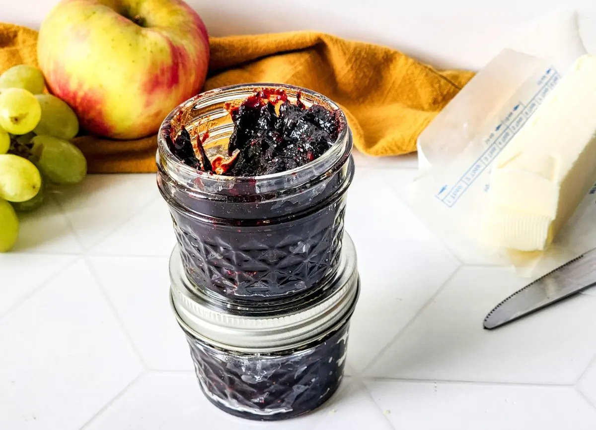 Two jars of mixed berry jam, one sitting on another.