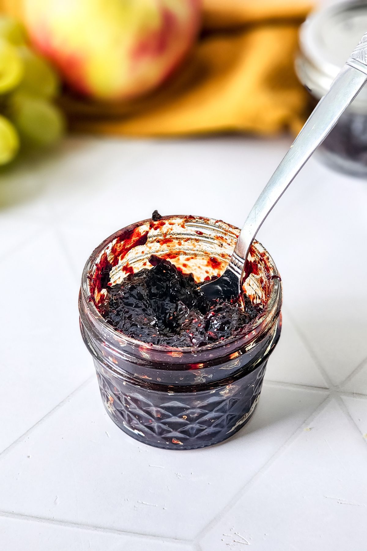 A spoon in a jar of Mixed Berry Jam.