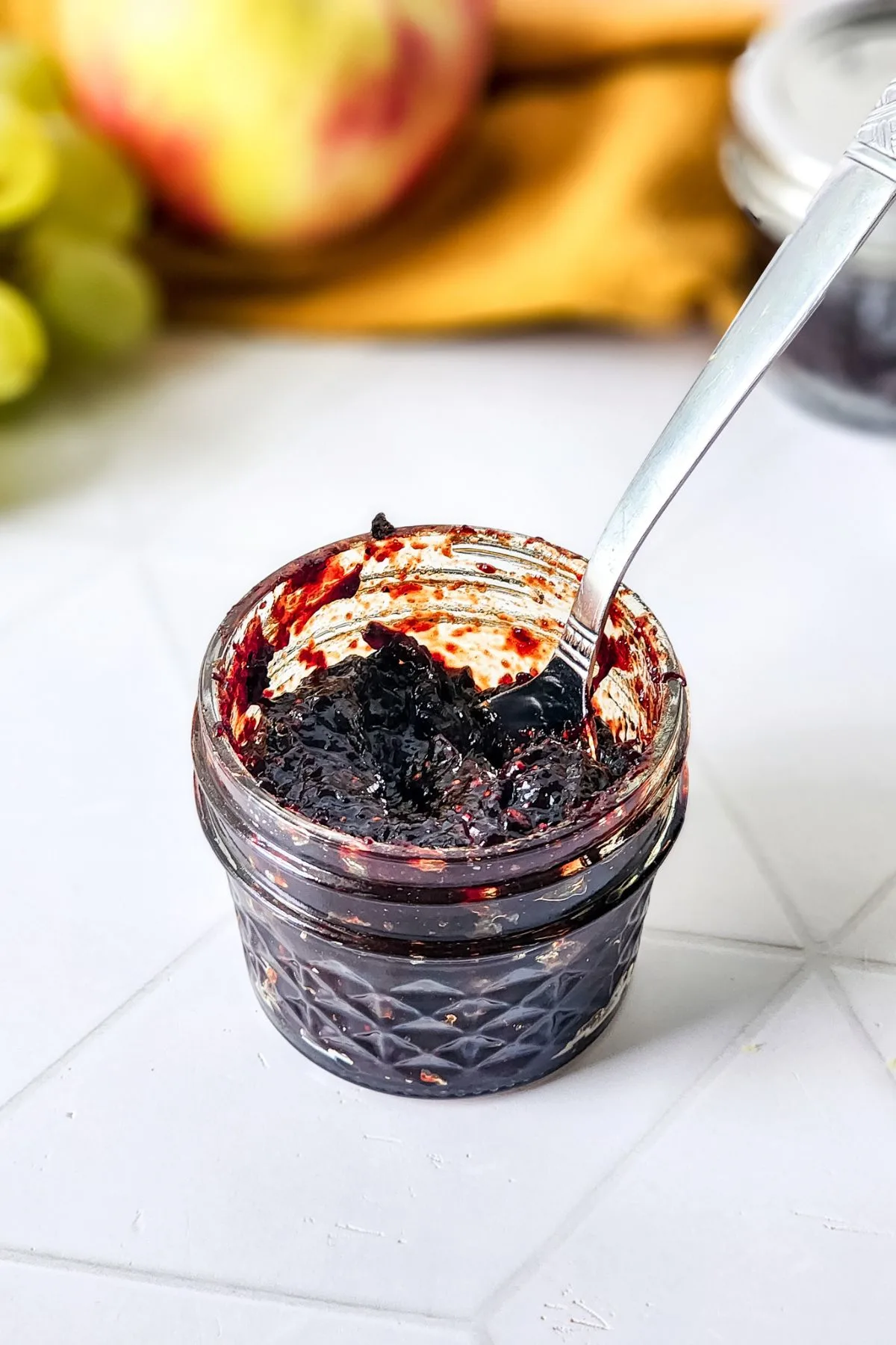 A spoon in a jar of Mixed Berry Jam.