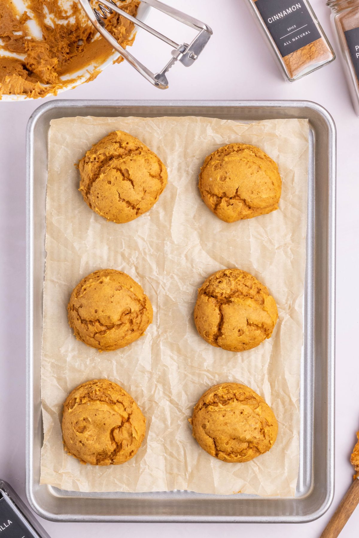 A parchment lined baking tray with fresh baked pumpkin cookies.