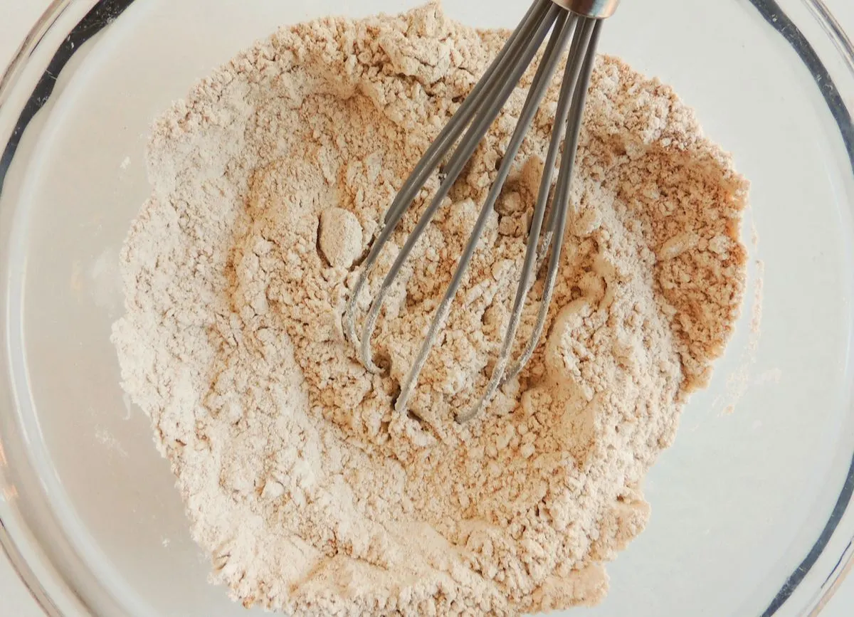 A mixing bowl of flour, brown sugar, cinnamon, clove, nutmeg, ginger, baking soda, and salt.