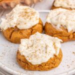 Close up looking at a few Pumpkin Cookies with cream cheese frosting on a plate.