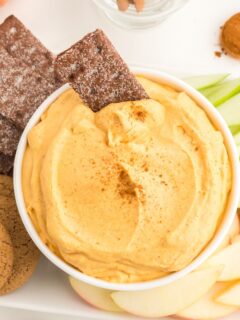 Looking down on a bowl of creamy pumpkin dip with dippers surrounding it.