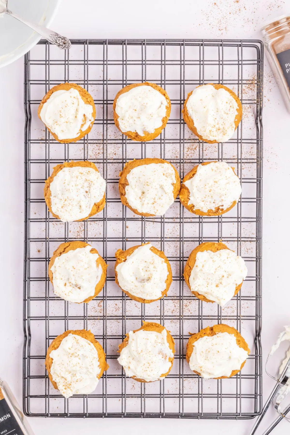 Pumpkin cookies with cream cheese frosting and pumpkin spice on top.