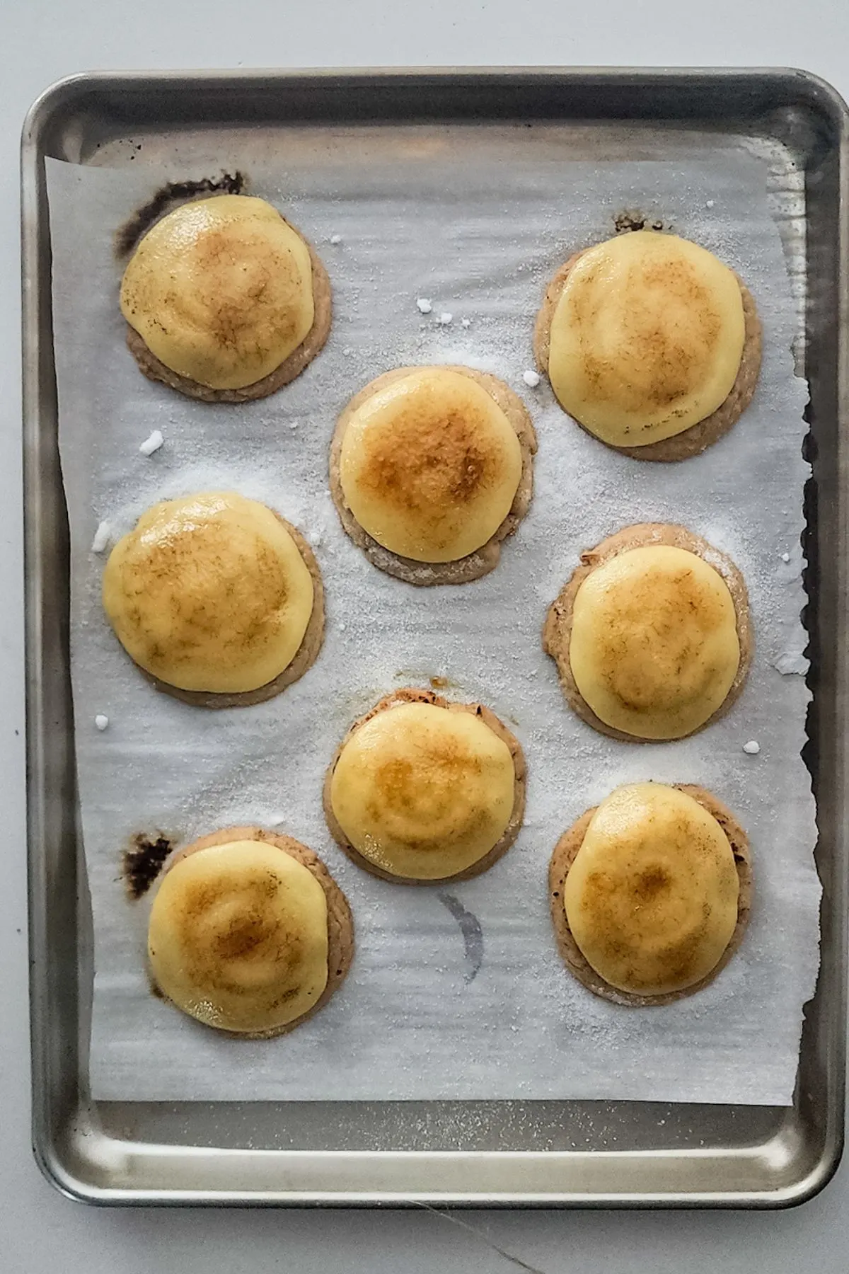 Freshly bruleed cookies on a parchment lined cookie sheet.