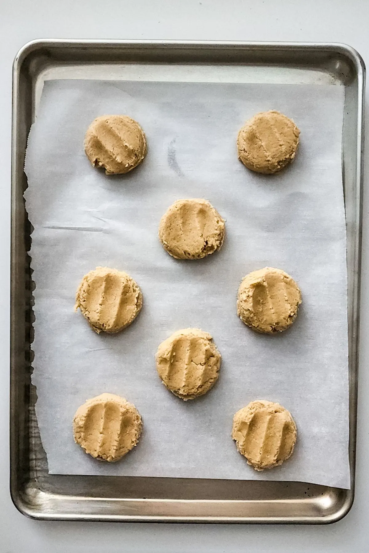 Cookie dough pressed down on a parchment lined baking sheet.