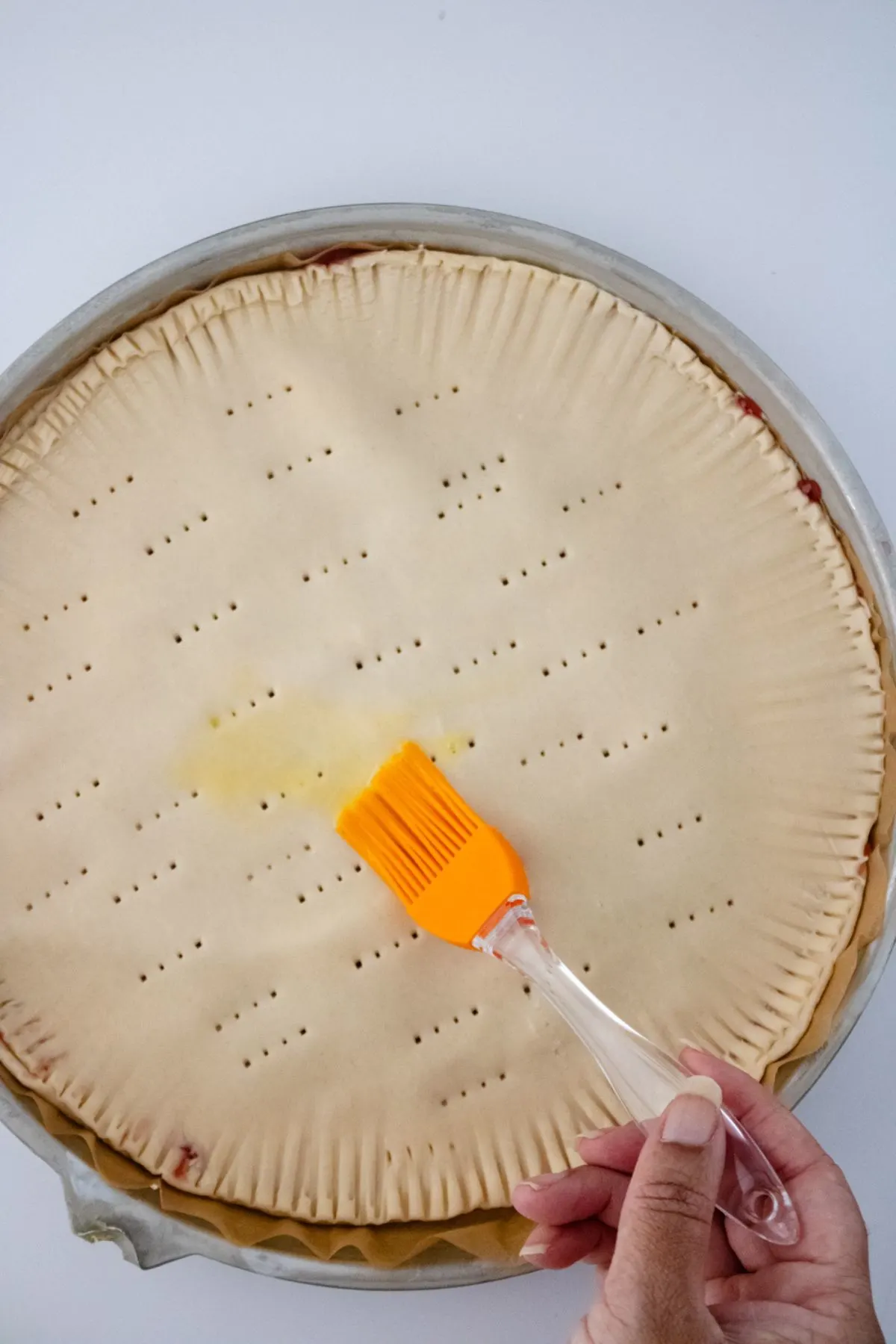 Egg wash being put on a pie crust.