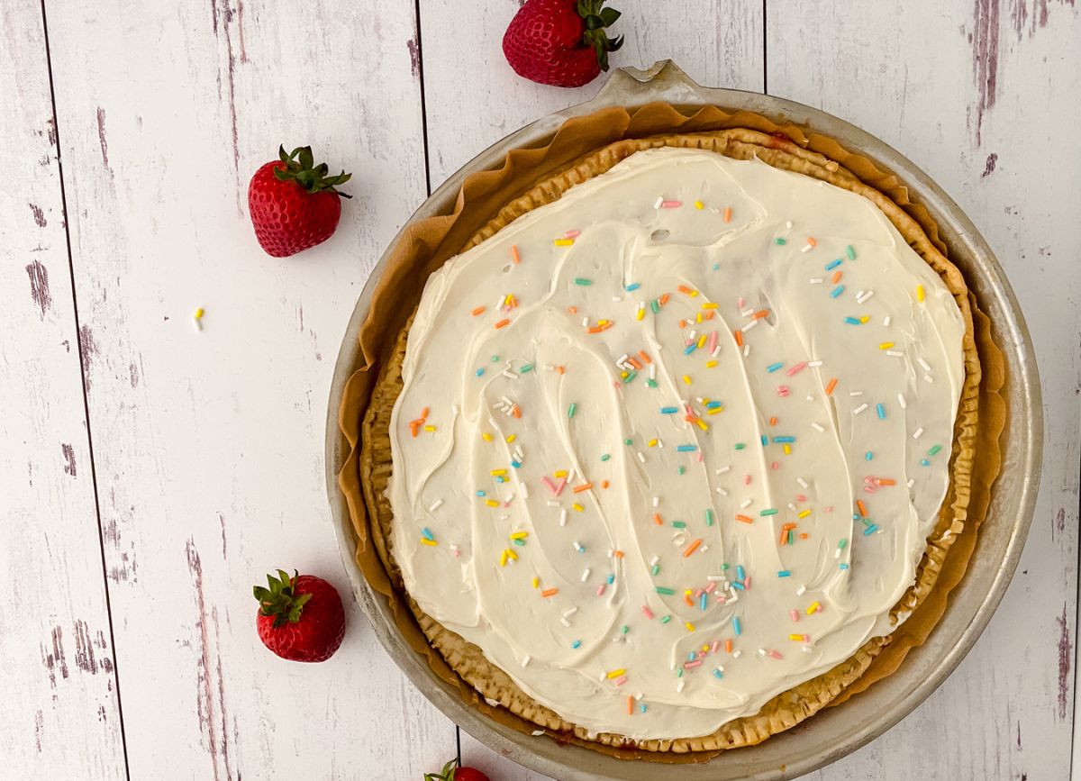 A Giant Pop Tart in a pie pan with strawberries around it.