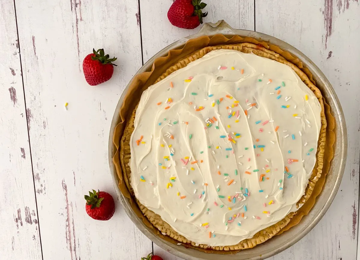 A Giant Pop Tart in a pie pan with strawberries around it.