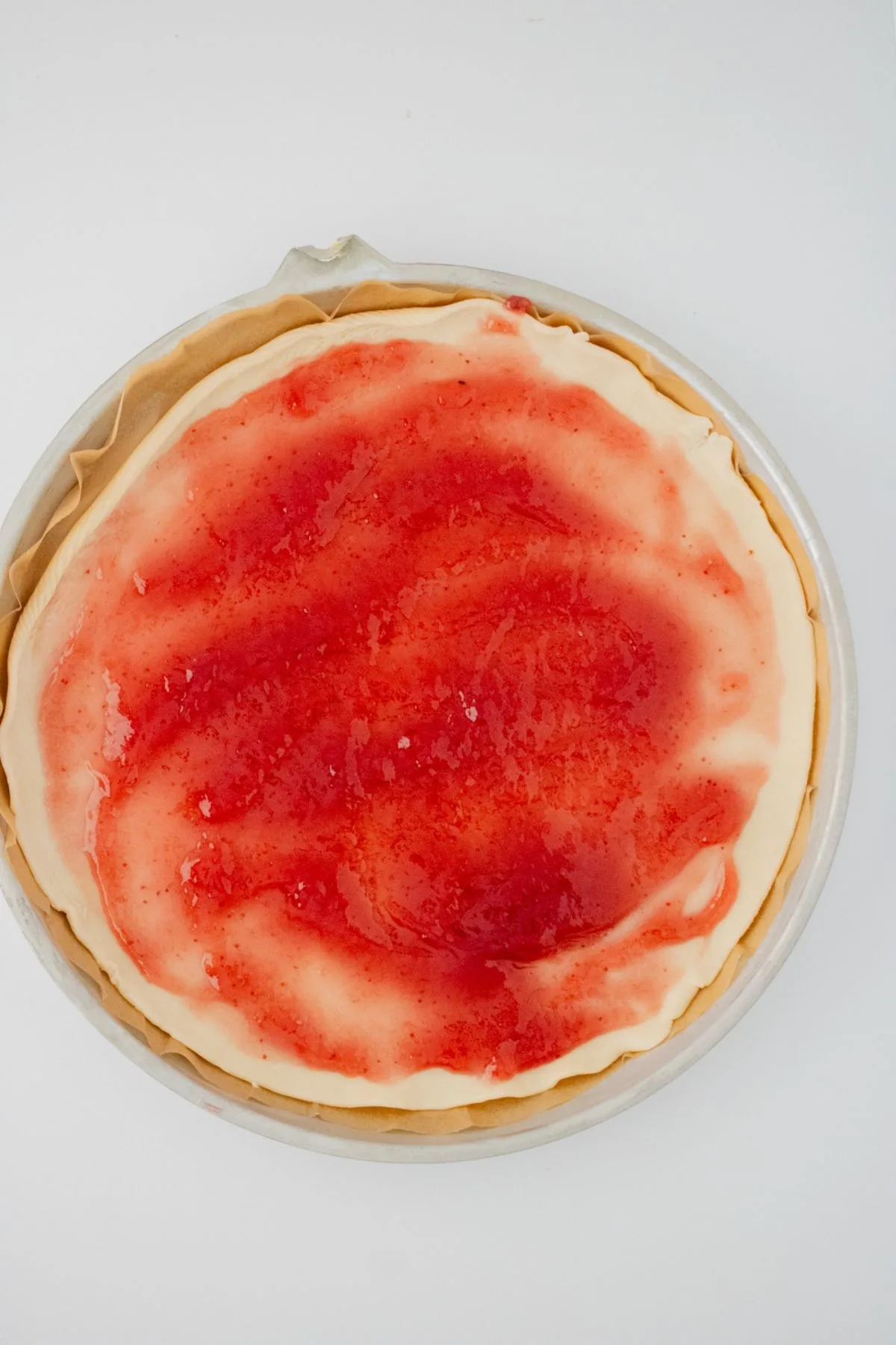Strawberry preserves on a pie crust.