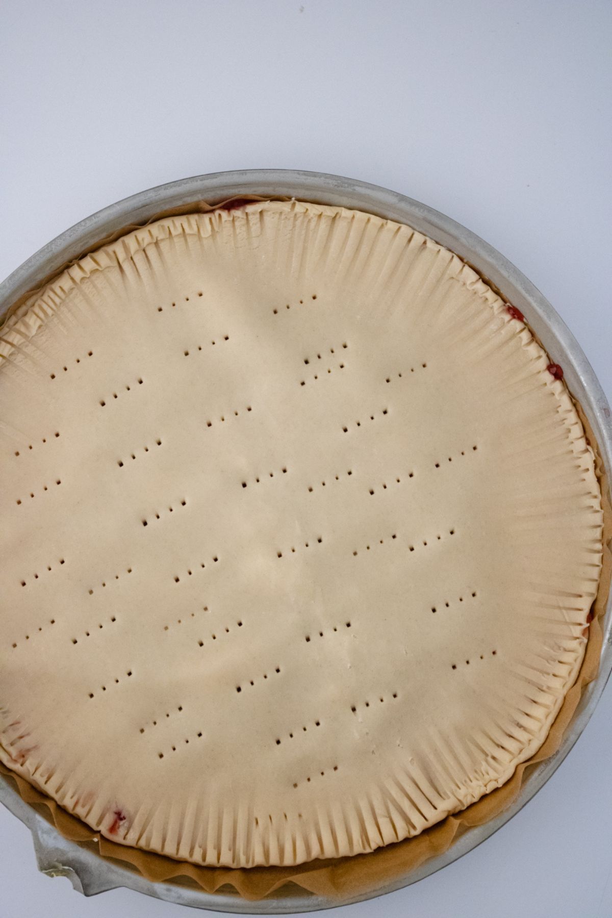 A pie crust with holes poked in the top.
