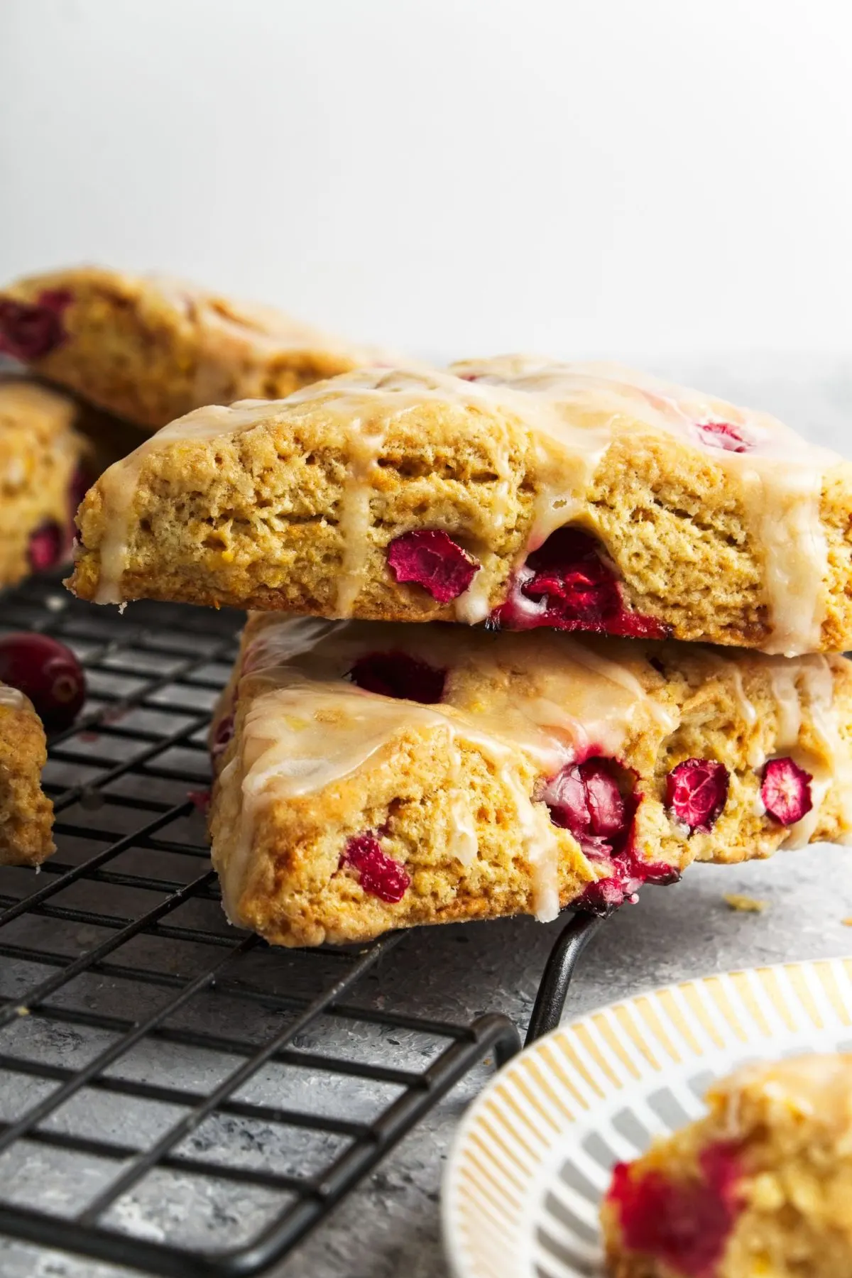 Two Cranberry Orange Scones sitting on top of one another on a wire rack.