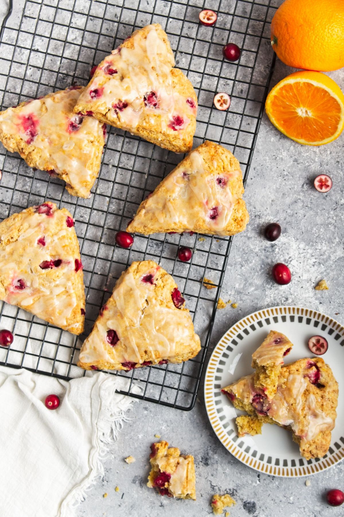 Looking down on a few freshly made homemade Cranberry Orange Scones, some on a wire rack, one on a plate.