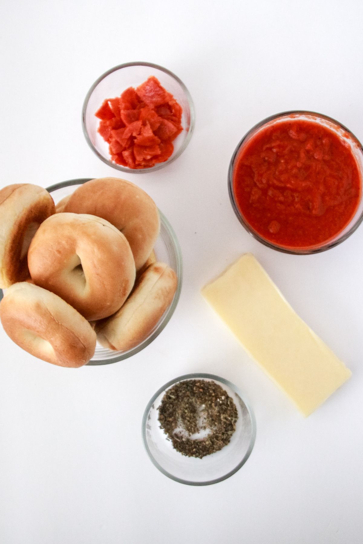 Bagels, block of mozzarella, pizza sauce, pepper and basil, and pepperonis. 